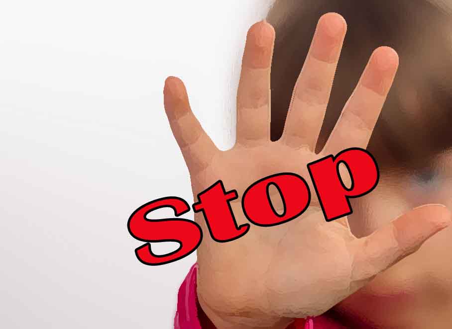 Young girl making stop gesture with her hand. Focus is on the hand. The face of the girl is blurred.